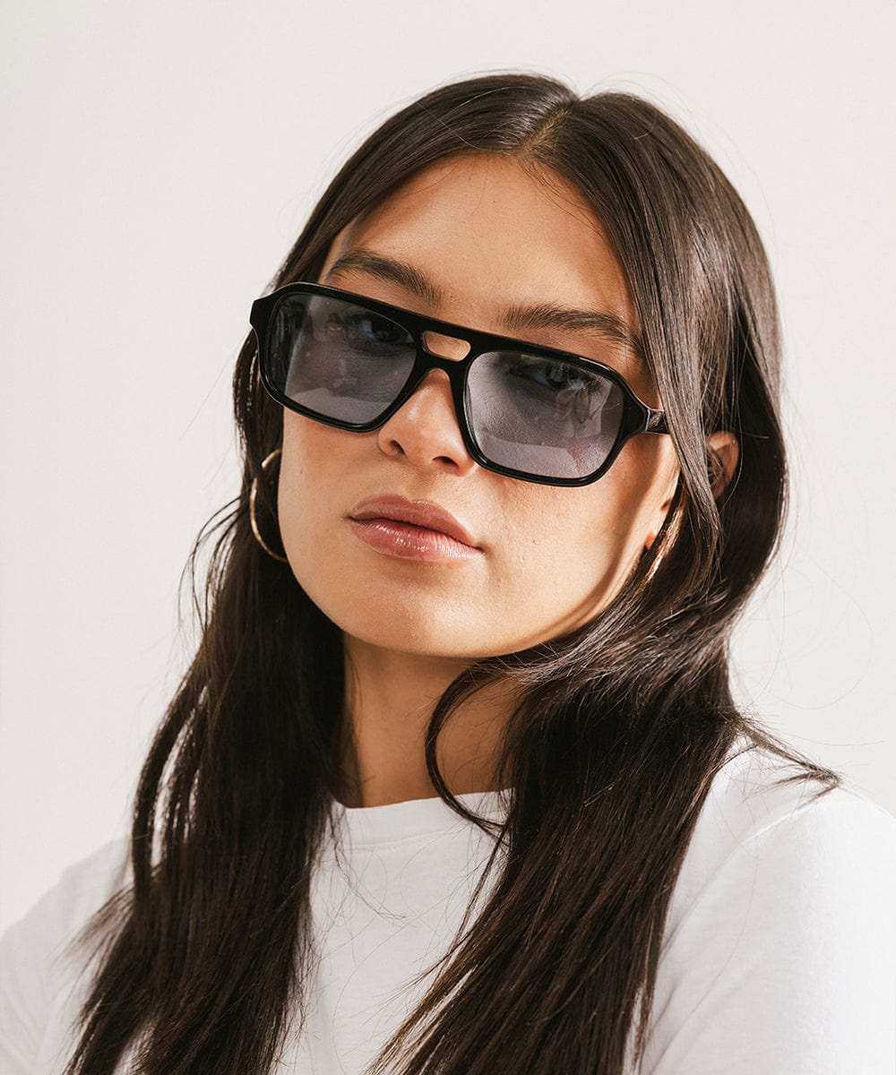 Woman wearing black sunglasses with a plain white background