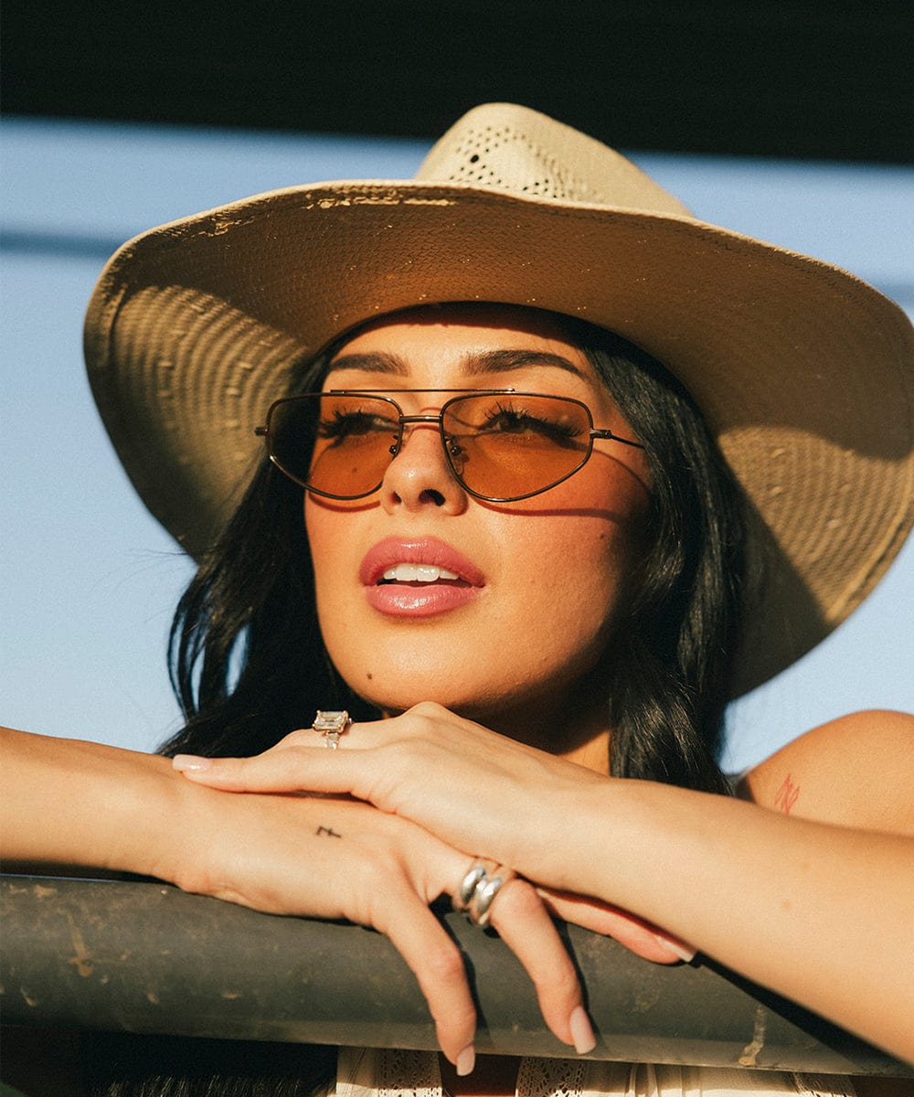Woman wearing a straw hat and sunglasses with a blue background