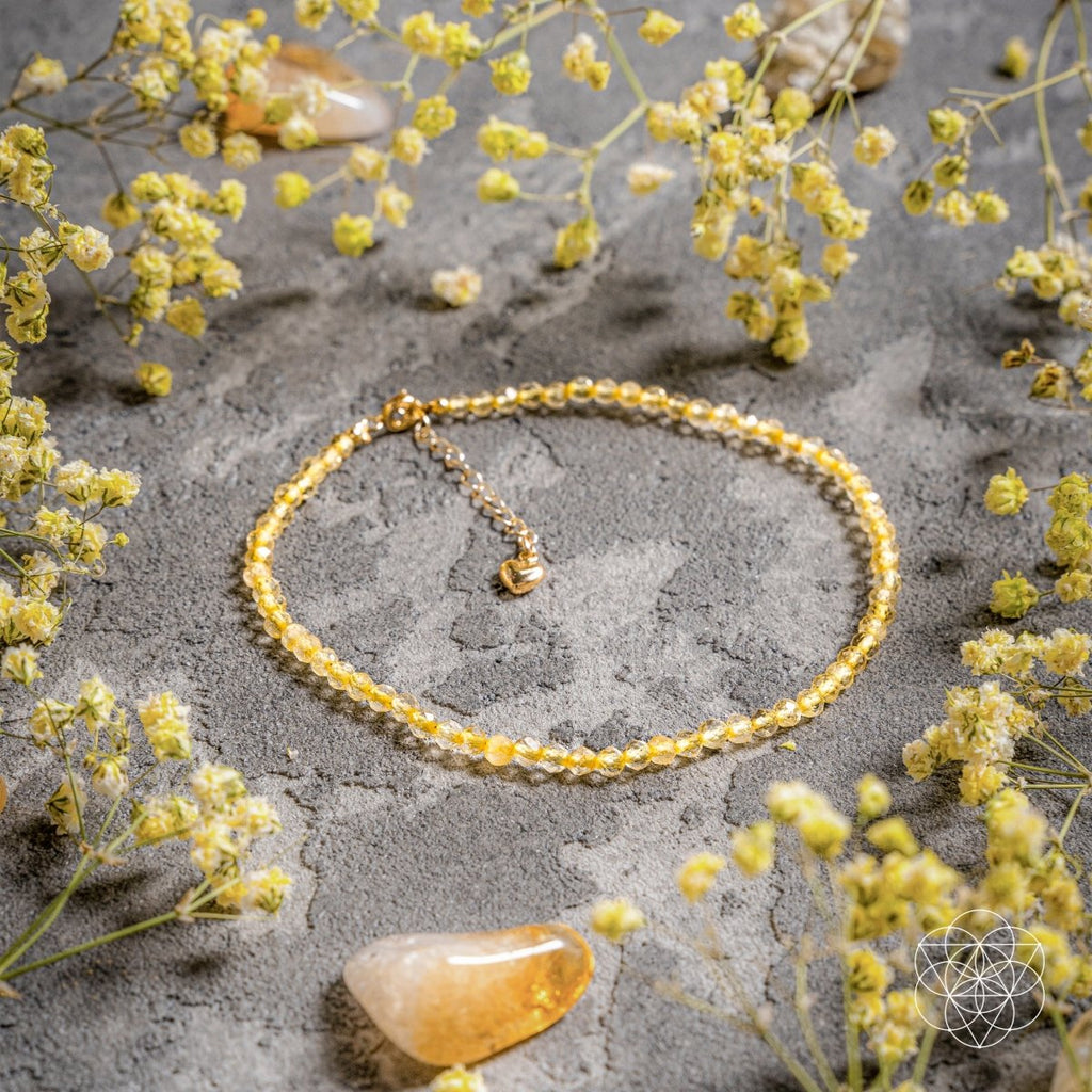 Gold bracelet on a gray surface with yellow flowers
