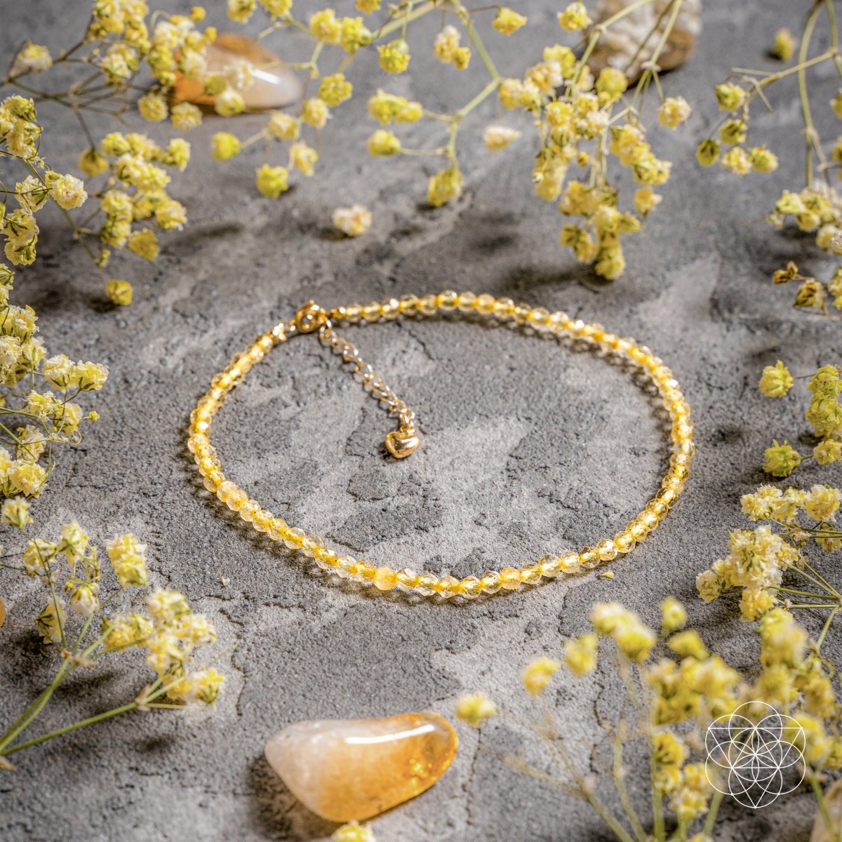 Gold bracelet on a gray surface with yellow flowers