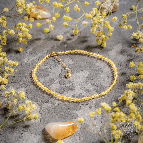 Gold bracelet on a gray surface with yellow flowers
