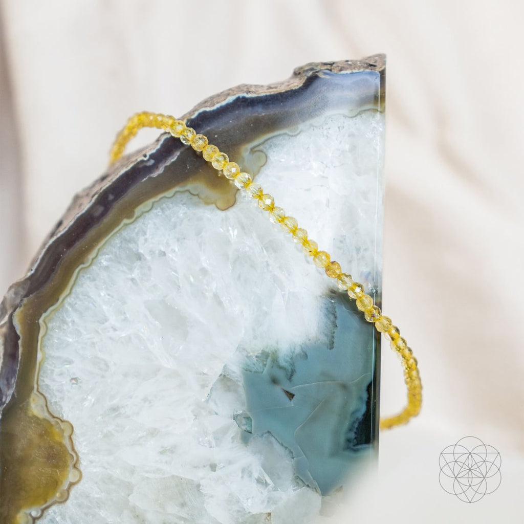 Yellow beaded bracelet on a large agate stone with a white background