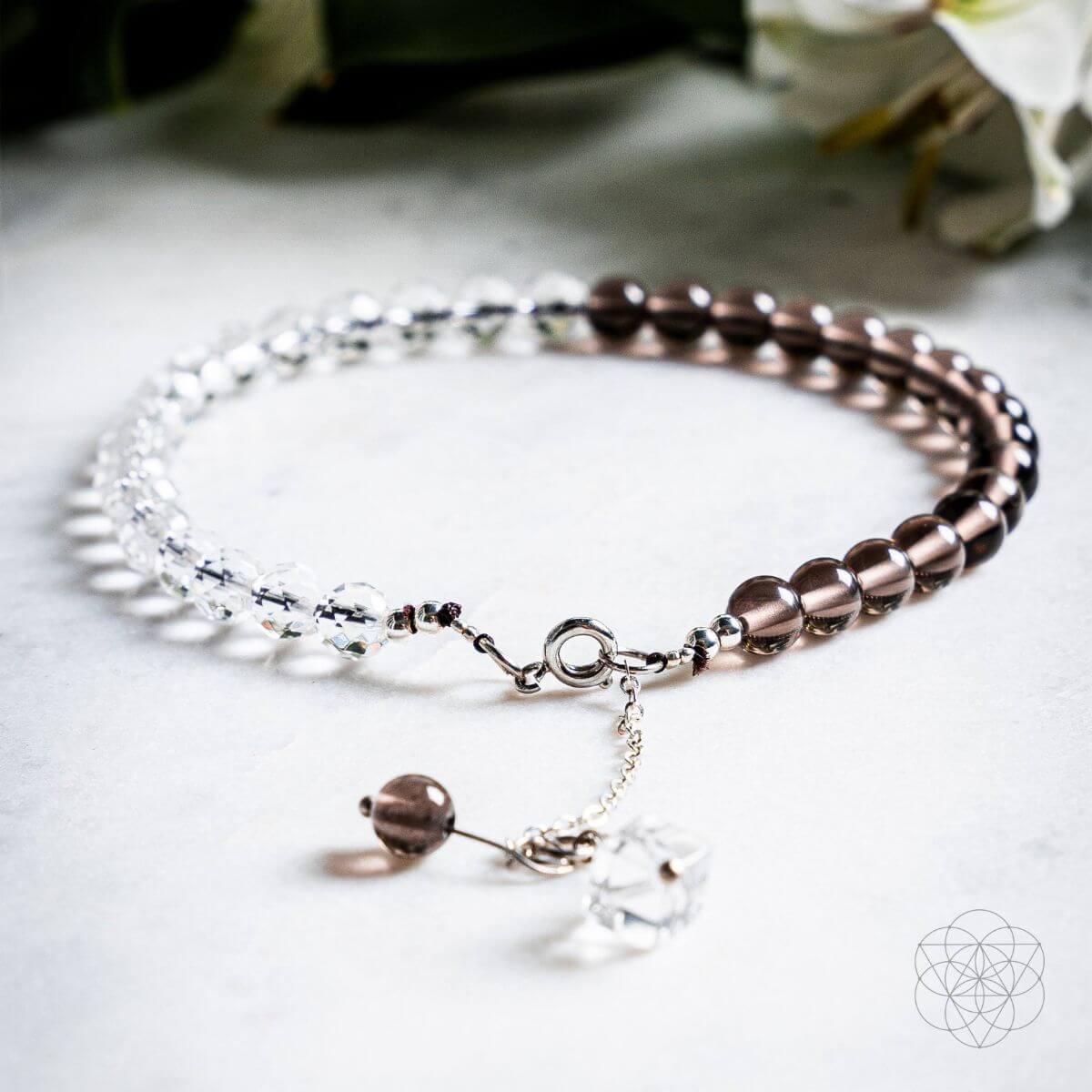 Two beaded bracelets on a light surface with a blurred floral background