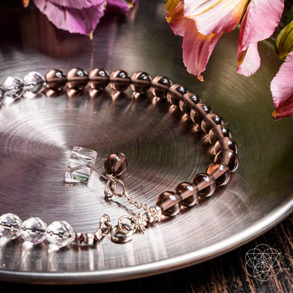 Bracelet with clear crystals on a metallic surface with pink flowers in the background