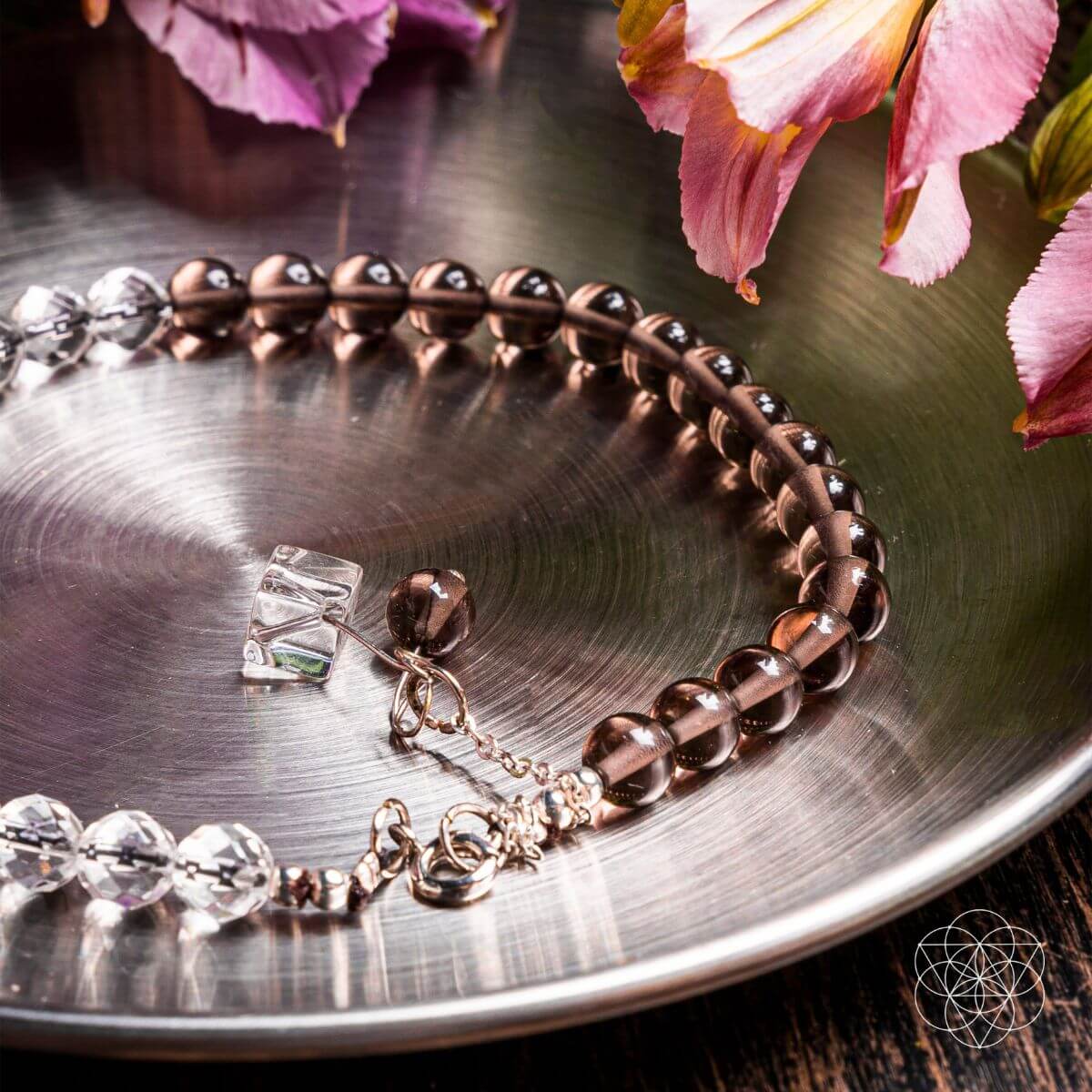 Bracelet with clear crystals on a metallic surface with pink flowers in the background